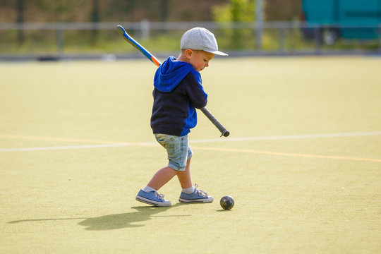 Small boy training playing field hockey with stick on the field