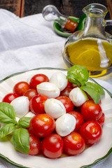 Italian soft cheese, young small balls mozzeralla cheese salad served with fresh basil, tasty ripe cherry tomatoes and Italian olive oil