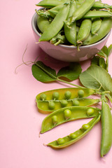 Fresh green ripe sugar snaps, sweet peas in bowl copy space close up on light pink background