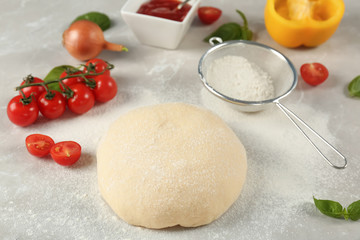 Fresh dough and ingredients for pizza on table
