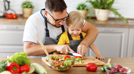 happy family father with son preparing vegetable salad