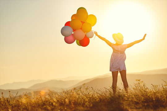 happy woman with balloons at sunset in summer