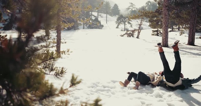 Young couple lying down in snow and making snow angel
