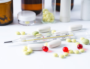 Medical bottles and pills, thermometer on a white background