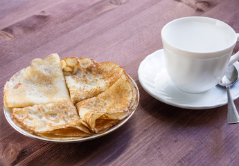 Hot pancakes on a plate and a cup of tea