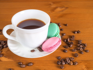 Cup with coffee, cakes and coffee beans on a wooden background