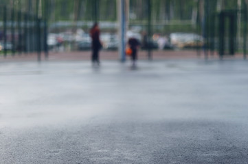 Obraz premium Wet asphalt in focus for text on the background of street basketball court on which people play
