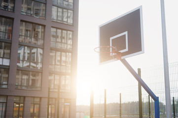 Street basketball court and basketball Hoop on sunset background.