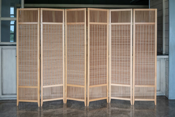 Woven wicker seamless pattern wooden partition on concrete floor.