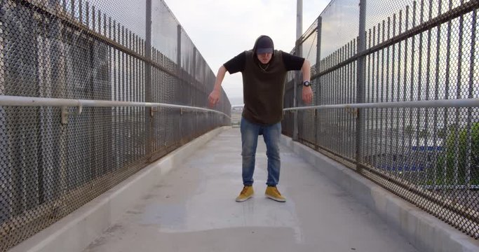Man hip hop dancing across freeway overpass in city at sunset
