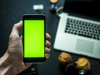 overhead view of hand with chroma key on the office dark table with laptop and notebook mockup