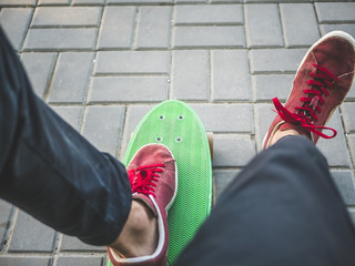 close up man's legs in sneakers sitting on the bench with skateboard