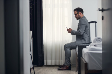 Businessman using smart phone at hotel room 