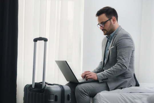 Businessman using laptop computer, working at his hotel room. Traveling for work. 