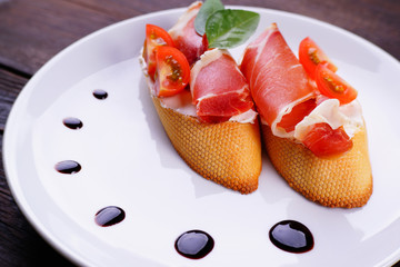 Italian antipasto- bruschetta with jamon. Prosciutto sandwich, appetizing popular mediterranean meals. Buffet, restaurant menu, banquet snack