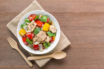 stir fried pork with black and sweet pepper in a ceramic dish on wooden table, copy space for text. homemade style healthy food concept.