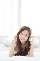 Naklejka premium Beautiful asian young woman enjoy listen music with headphone while lying in bedroom, relax girl with earphone internet online, leisure and technology concept.