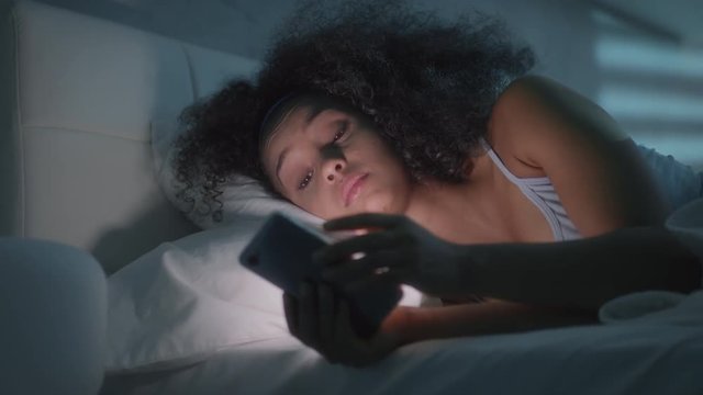 Young African American Woman Texting With Smartphone In Bed