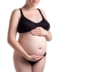 A happy pregnant woman holds her tummy hands and smiles, expectant mother isolated on white background.