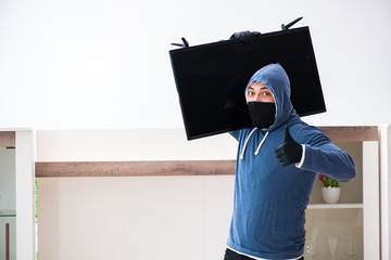 Man burglar stealing tv set from house