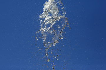 Splashes of flying water from the fountain against the blue sky