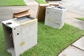 Broken and rusted gas furnace sitting on curb for trash pick up