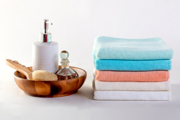 Ceramic soap, shampoo bottles and white cotton towels on white background.