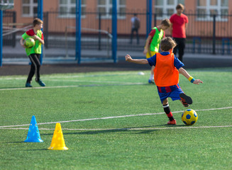 Obraz premium Cute boy playing football, happy child enjoying soccer. Kids activities, little footballer. training on the field in the summer