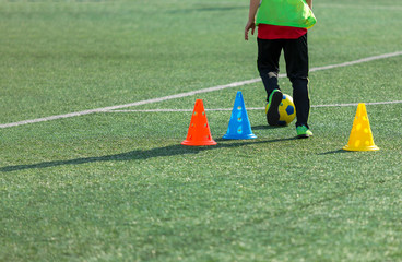 Obraz premium Cute boy playing football, happy child enjoying soccer. Kids activities, little footballer. training on the field in the summer