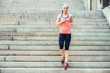 Obraz premium Woman running on steps in New York Central Park listen to music and wearing sport clothes at summer time