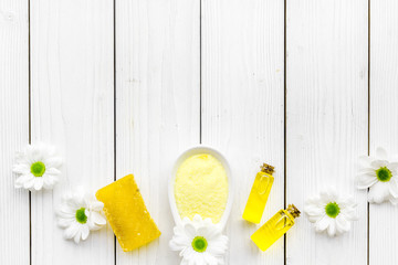 Natural organic spa cosmetics for skin care with chamomile. Spa salt, oil, soap on white wooden background top view copy space