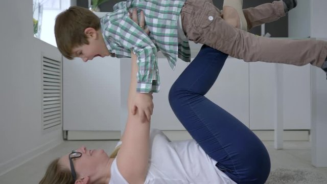 home leisure, mother with son fool around lying on floor indoors close-up