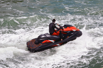 Over head view of a jet skier riding waves on a red jet ski on the Florida Intra-coastal Waterway near Miami Beach.