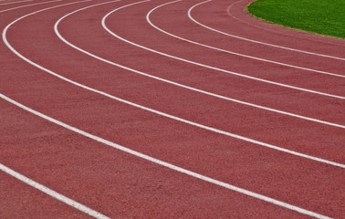 White painted running lanes on a red track with green grass