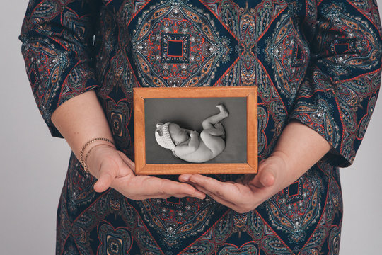 a pregnant woman holding a photo of her unborn child. Isolated photo on white background