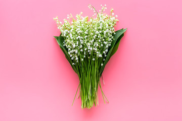 May flowers. Bouqet of lily of the valley flowers on pastel pink background top view copy space