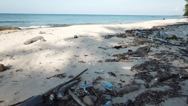 Plastic bottles aqnd bags pollution on a beach. Panning shot by aerial drone.  