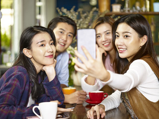 young asian adults taking selfie in coffee shop