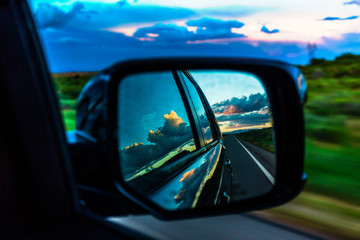 Storm clouds reflection in mirror of moving automobile