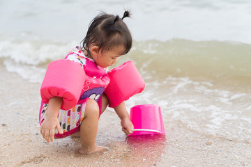 Asian baby girl playful on the beach background.