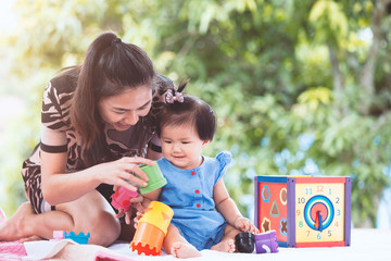 Happy asian mother and cute little baby girl playing with the toy together with fun and love