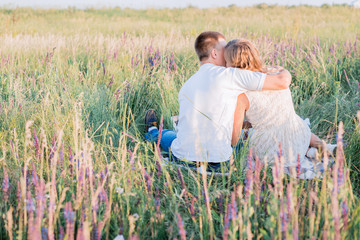 Cute young couple in love sitting and hugging in a field of lavender flowers