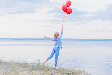 Girl holding colorful balloons in her hand and staying on one leg