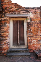 Travel Thailand - Old door wood and wall brick as a background in Wat Phutthaisawan, Ayutthaya Historical Park. Space for text in template. Black and orange brick of Temple.  