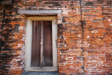 Travel Thailand - Old door wood and wall brick as a background in Wat Phutthaisawan, Ayutthaya Historical Park. Space for text in template. Black and orange brick of Temple.  