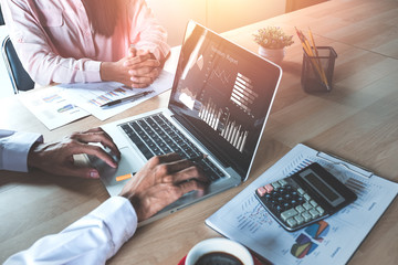Two colleagues discussing data with  new modern computer laptop on desk table. Close up business...