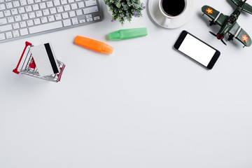 Modern white office desk with computer keyboard, notebook,pen,smart phone,credit card and cup of coffee.Top view with copy space