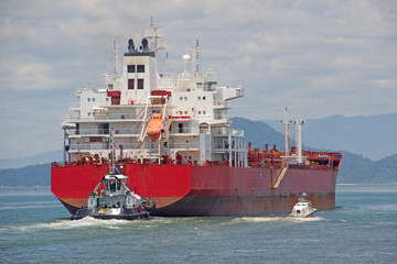 A tanker is assisted by pilot and a tugboat