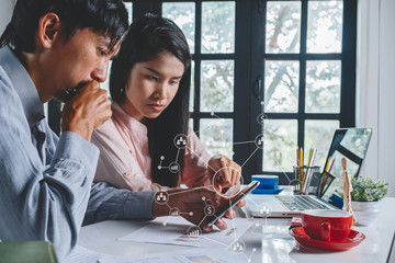 Two business people sitting at office and discussing project on smart phone Young businesswoman and businessman looking at smart phone.