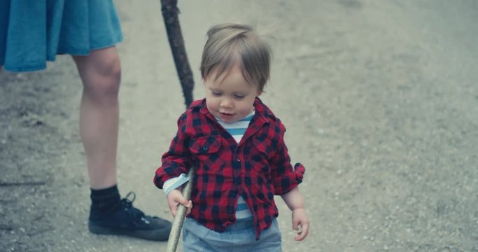 Little toddler with his mother carrying big stick
